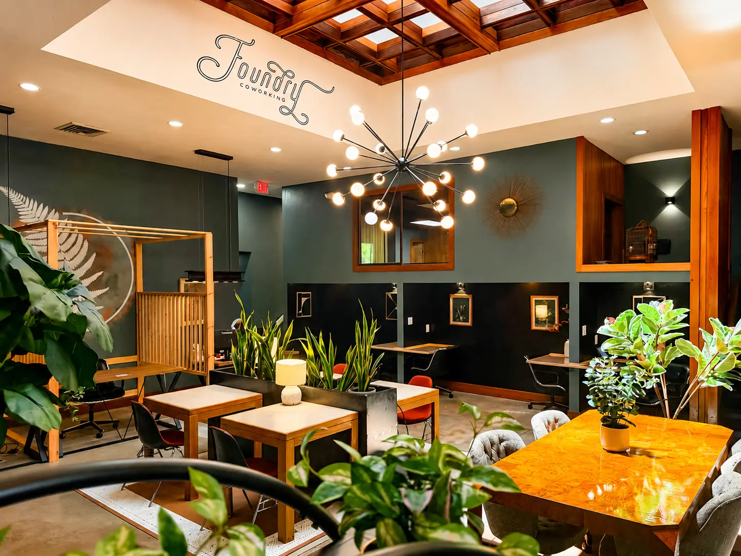 A bright coworking lounge with couches, plants, and desks